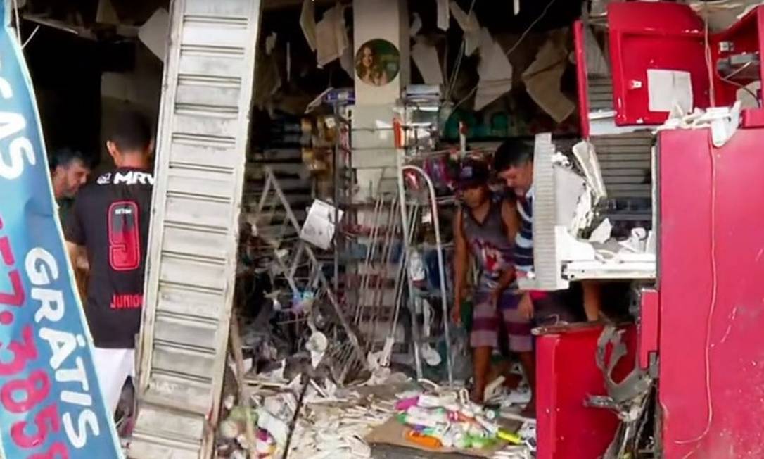 Funcionários limpam a famrácia destruída por explosão de caixa eletrônico provocada por criminosos, em Nova Iguaçu Foto: Reprodução/ Tv Globo