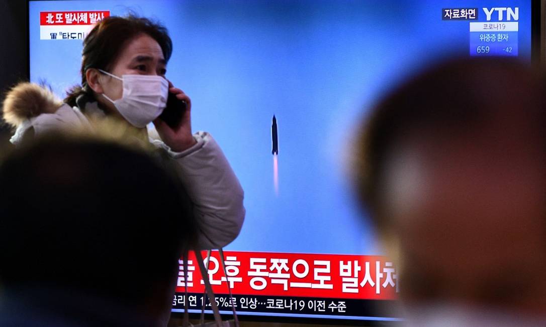 Em Seul, mulher caminha em frente de monitor que mostra imagem de lançamento de míssil Foto: ANTHONY WALLACE / AFP