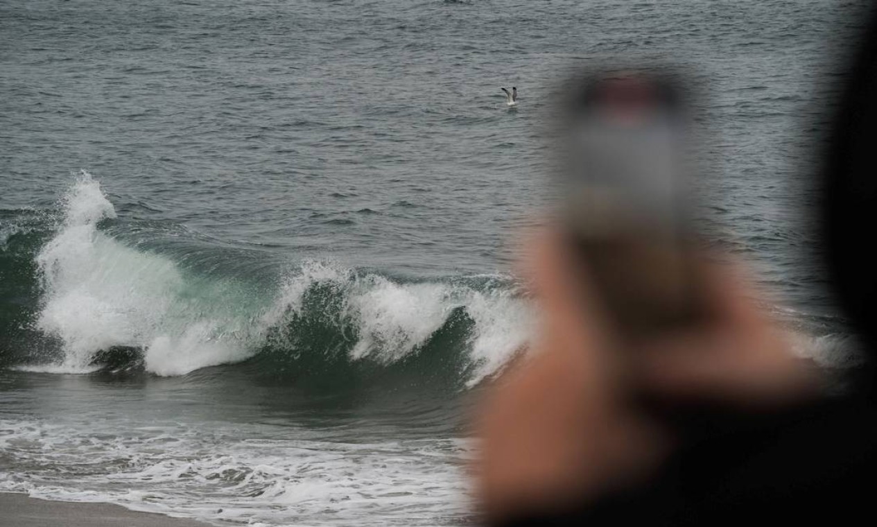 Homem filma com o celular ondas em Seal Beach, California, Estados Unidos Foto: BING GUAN / REUTERS