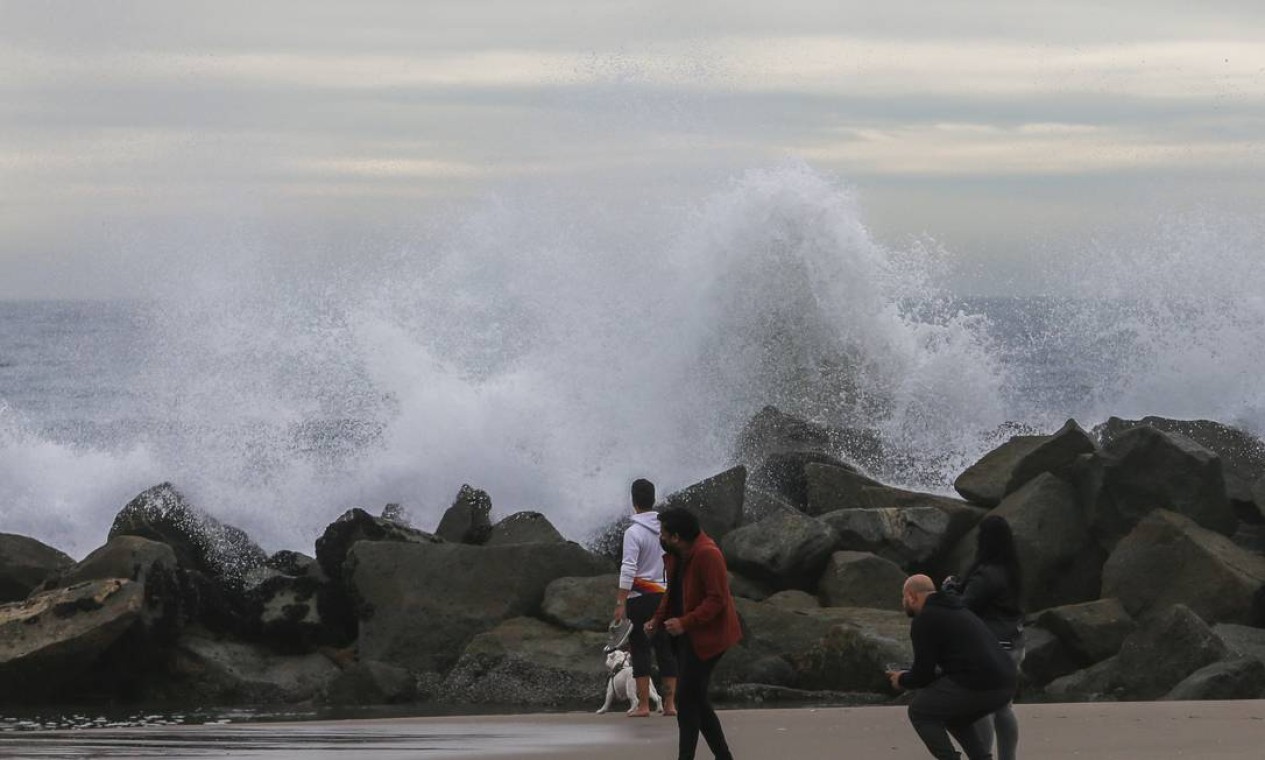 Pessoas observam, de perto, grandes ondas no quebra-mar na praia de Venice, em Los Angeles, Califórnia Foto: Apu Gomes / AFP