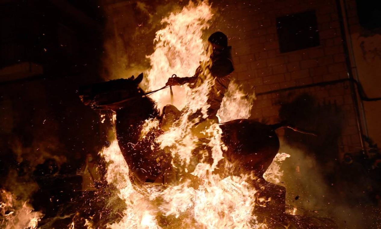Um cavaleiro cruza uma fogueira na aldeia de San Bartolome de Pinares, na província de Ávila, Espanha, durante a tradicional festa religiosa de "Las Luminarias" em homenagem a Santo Antônio, padroeiro dos animais Foto: PIERRE-PHILIPPE MARCOU / AFP