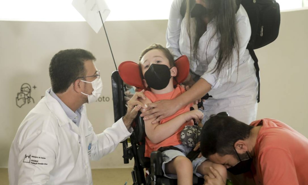 Paulo Silva chora de emoção enquanto o filho Davi recebe a primeira dose da vacina contra Covid-19, no Museu do Amanhã Foto: Gabriel de Paiva / Agência O Globo