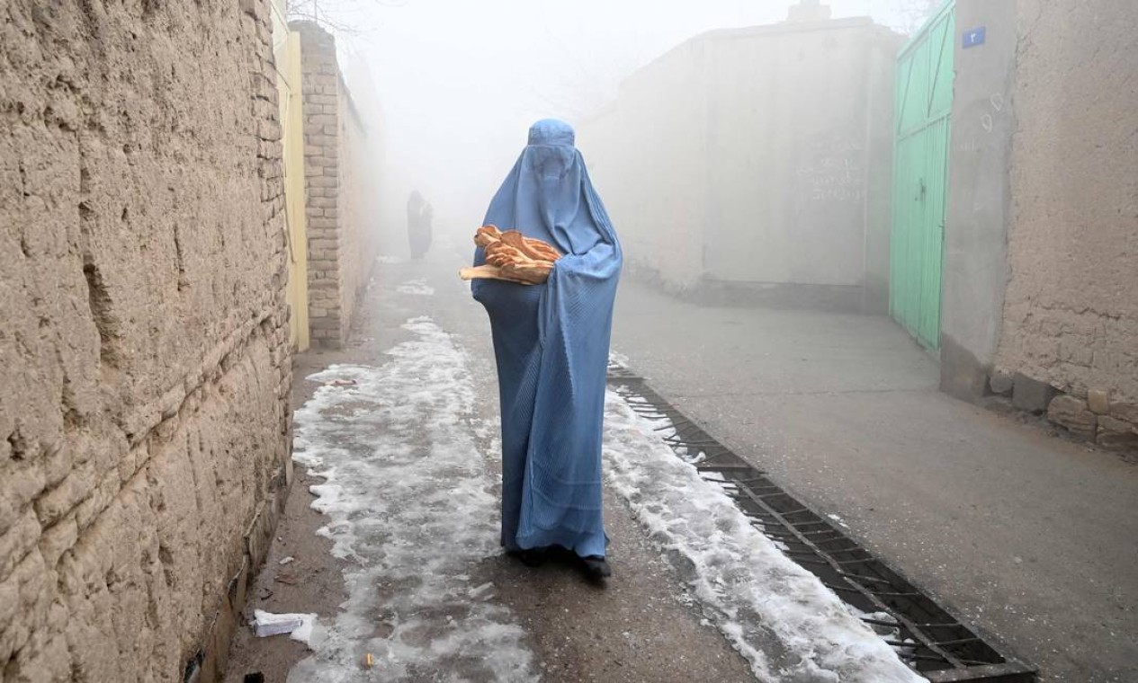 Mulher afegã carrega pães doados por iniciativa contra a fome em Cabul Foto: WAKIL KOHSAR / AFP