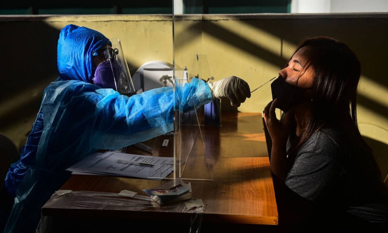 Profissional de saúde coleta amostra de paciente para teste de Covid-19, em uma estação de trem em Quezon City, no subúrbio de Manila Foto: MARIA TAN / AFP