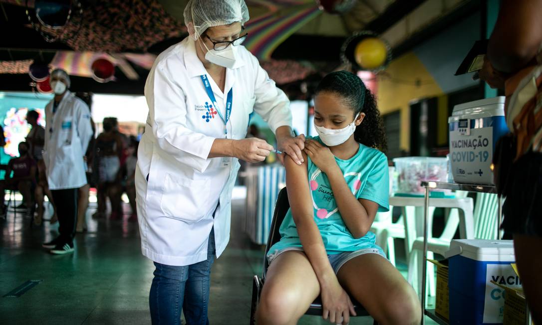 Menina recebe vacina contra a Covid-19 na Lona Cultural João Bosco, em Vista Alegre, no Rio. Foto: Brenno Carvalho / Agência O Globo