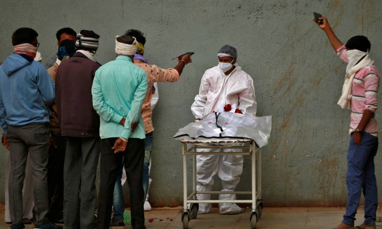 Homens tiram fotos do corpo de seu parente depois que ele morreu de COVID-19, em um hospital em Ahmedabad, Índia Foto: AMIT DAVE / REUTERS