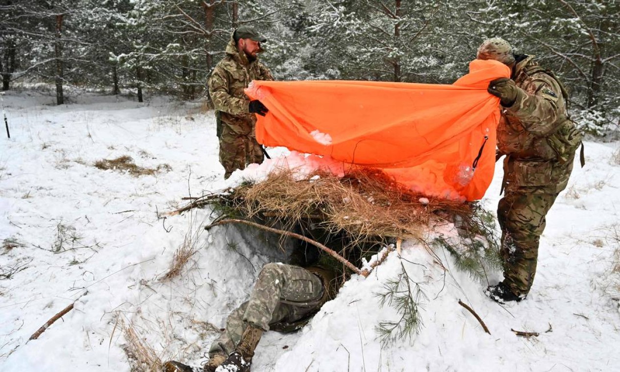 Civis ucranianos aprendem a construir um abrigo na neve como parte de um curso intensivo de técnicas de sobrevivência, em uma floresta nos arredores de Kiev Foto: GENYA SAVILOV / AFP