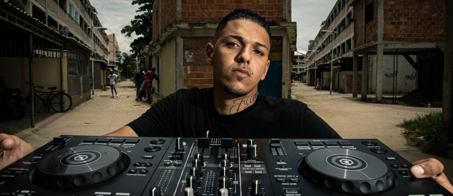 O produtor musical e DJ Chris Beats ZN, de 23 anos, com seu equipamento de trabalho, na favela onde mora: "Tomara que a situação melhore, porque minha região não tem nada" Foto: Hermes de Paula / Agência O Globo