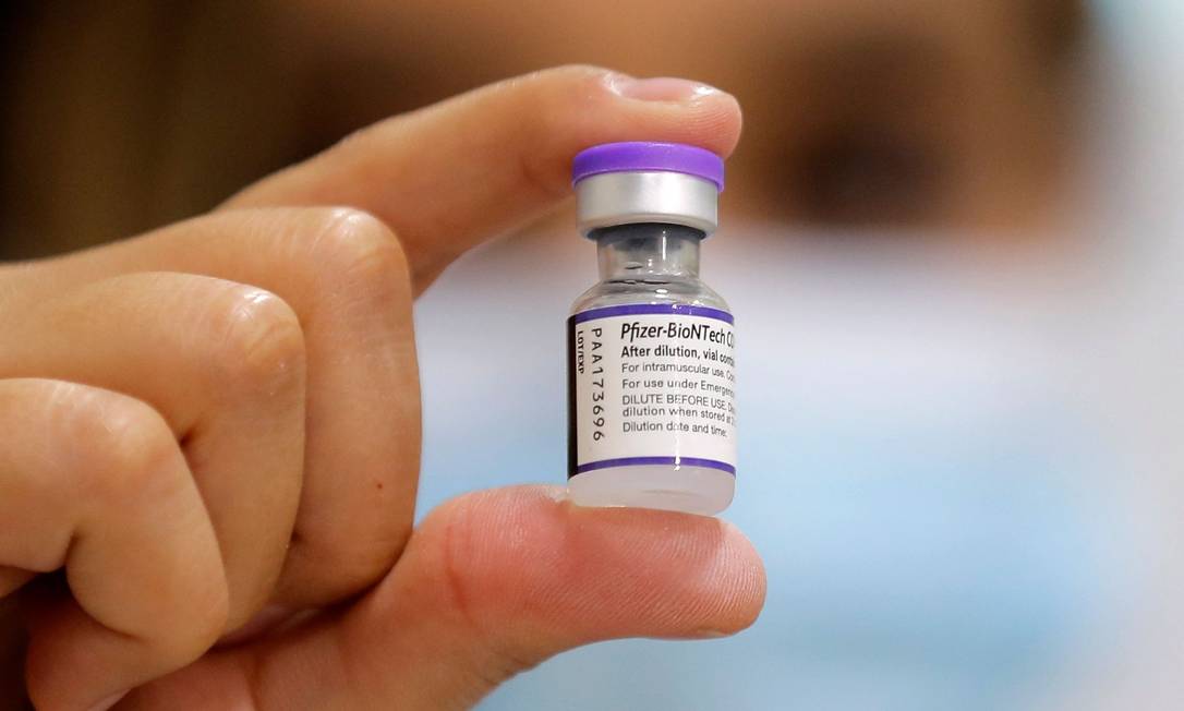 Profissional de saúde segura frasco com vacina da Pfizer contra Covid-19 Foto: JAVIER TORRES / AFP