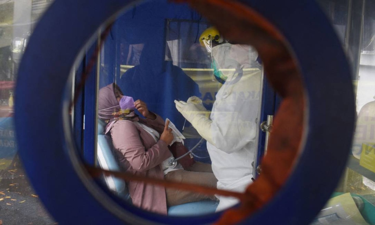 Trabalhadores médicos realizam um exame de saúde antes de fazer testes de PCR a Covid-19 em uma escola em Bandung, Java Ocidenta, Indonésia Foto: TIMUR MATAHARI / AFP