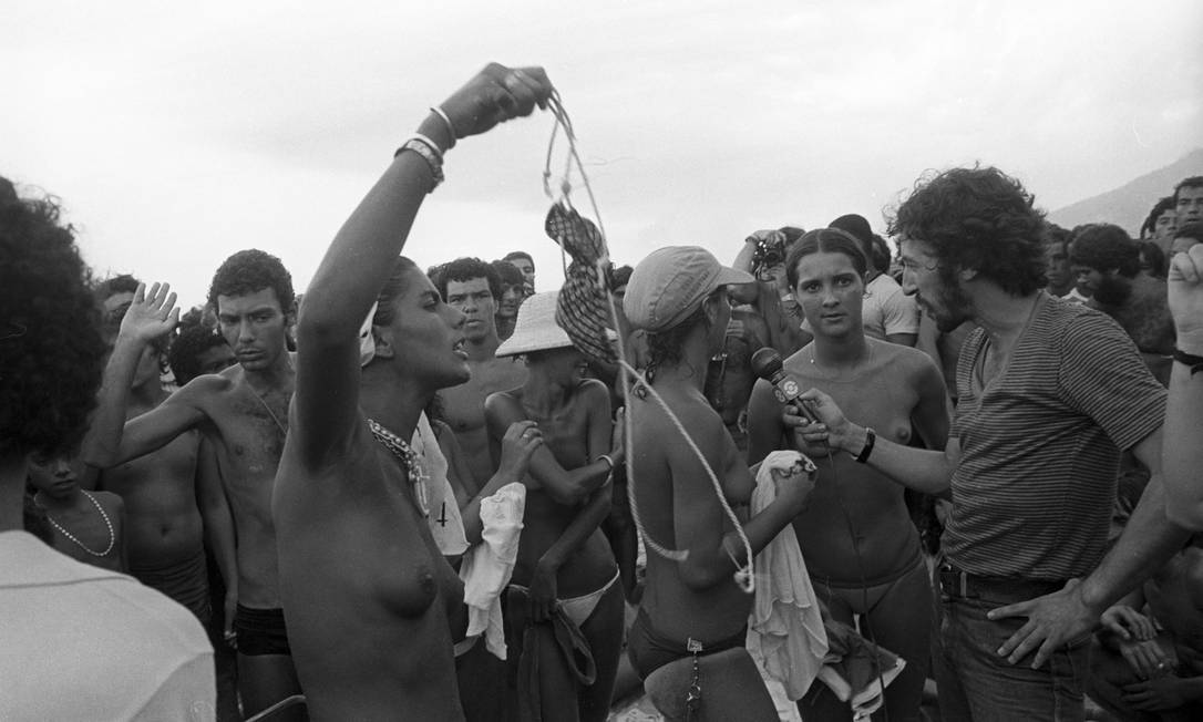 Cercada por homens descamisados, mulheres dão entrevistas para repórter depois de causarem tumulto por tirarem a parte de cima do biquíni em 1980 Foto: Eurico Dantas / Agência O Globo - 13/02/1980