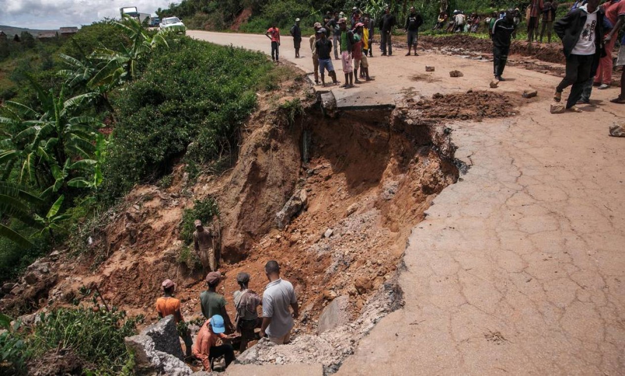 Moradores observam a estrada RN25 parcialmente desmoronada em Ranomafana, após a passagem do ciclone Batsirai. A trormenta matou mais de 20 pessoas, e deixou 55.000 desalojados em Madagascar Foto: RIJASOLO / AFP
