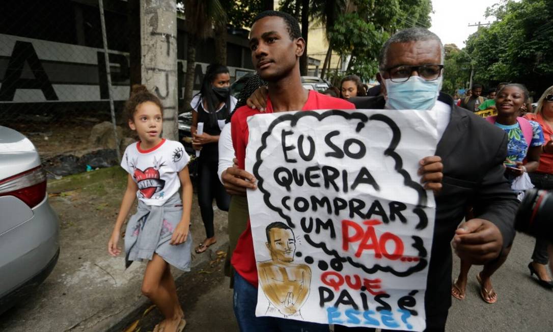 Yago de Souza, já livre, com um cartaz em que diz que "só queria comprar um pão" e a pergunta: "que país é esse? Foto: Domingos Peixoto / Agência O Globo