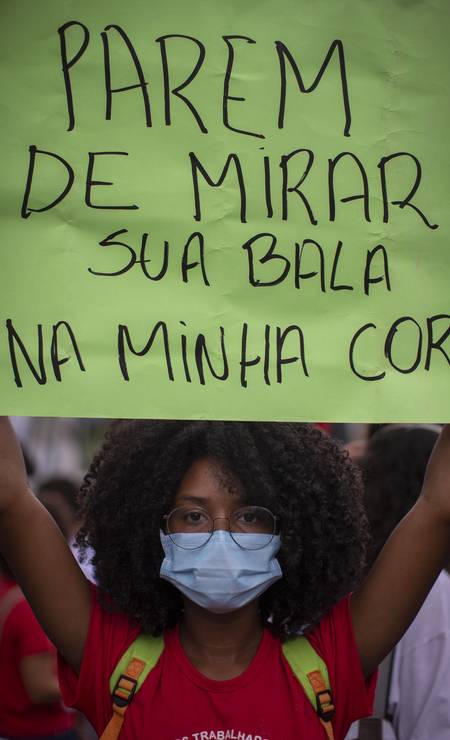 Jovem militante, usando máscara de proteção, segura cartaz durante manifestação Foto: Marcia Foletto / Agência O Globo