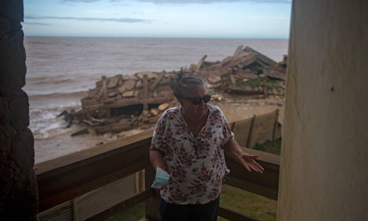 Sônia Ferreira, de 77 anos, mostra os escombros de um prédio visto de sua varanda. Ela abandonou sua casa em 2019, quando a água começou a carcomer o muro dos fundos Foto: MAURO PIMENTEL / AFP