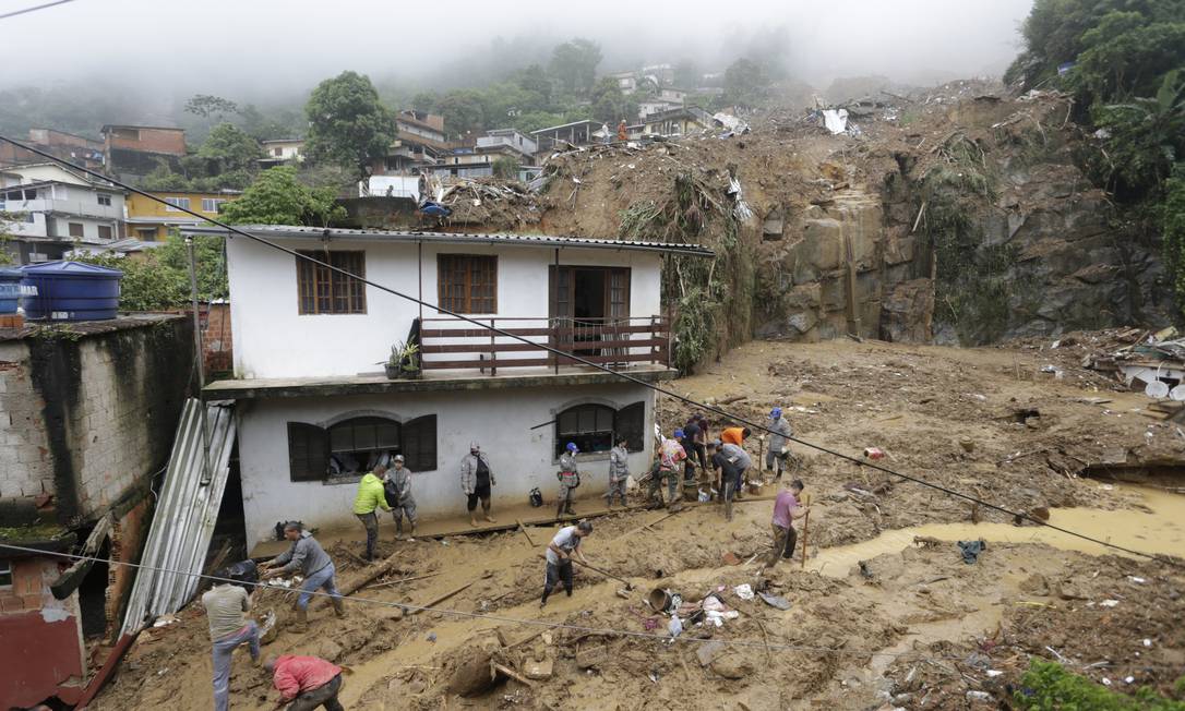 Munidos de enxadas, moradores removem lama e escombros Foto: Domingos Peixoto / Agência O Globo