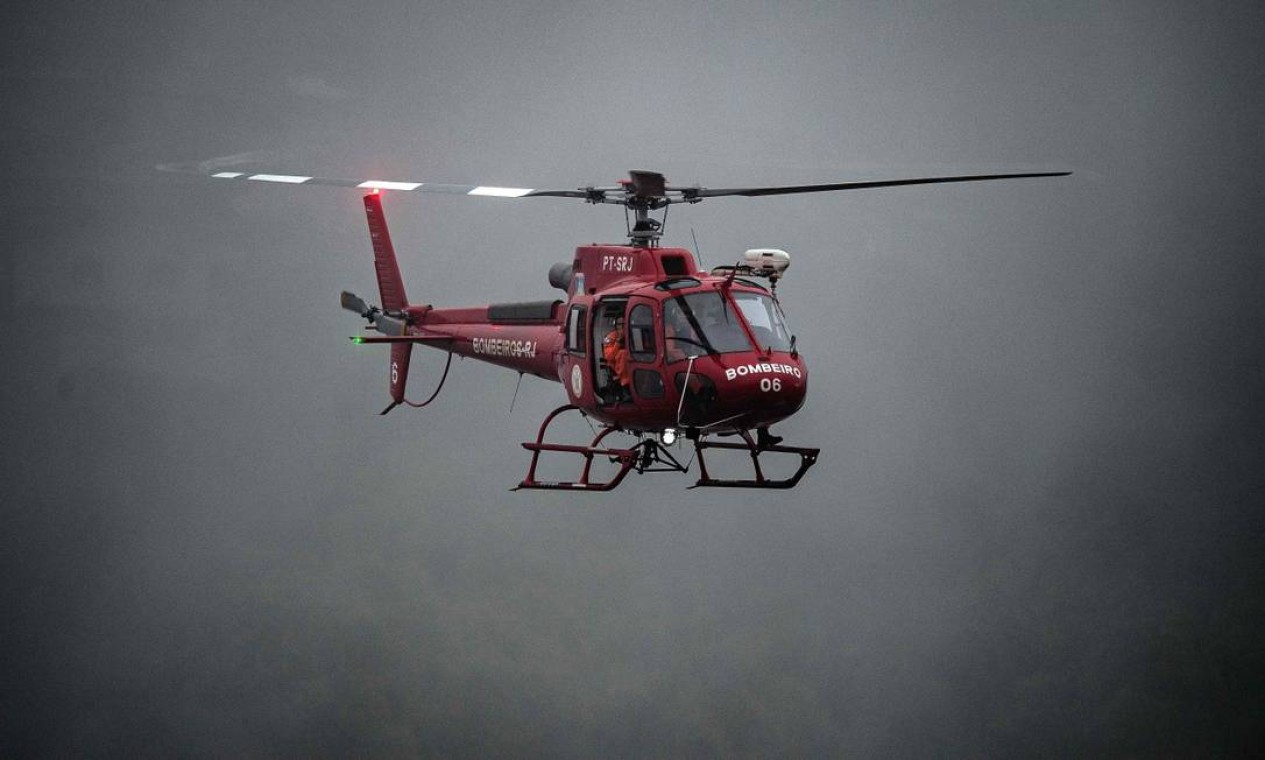 Helicóptero do Corpo de Bombeiros sobrevoa áreas atingidas, auxiliando na busca por vítimas Foto: CARL DE SOUZA / CARL DE SOUZA / AFP