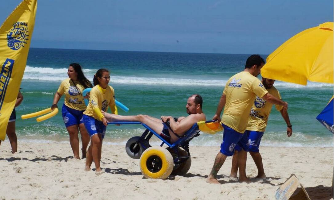 Banho de mar. Voluntários levamparticipante para a areia após mergulho na cadeira anfíbia Foto: Divulgação/Praia para Todos
