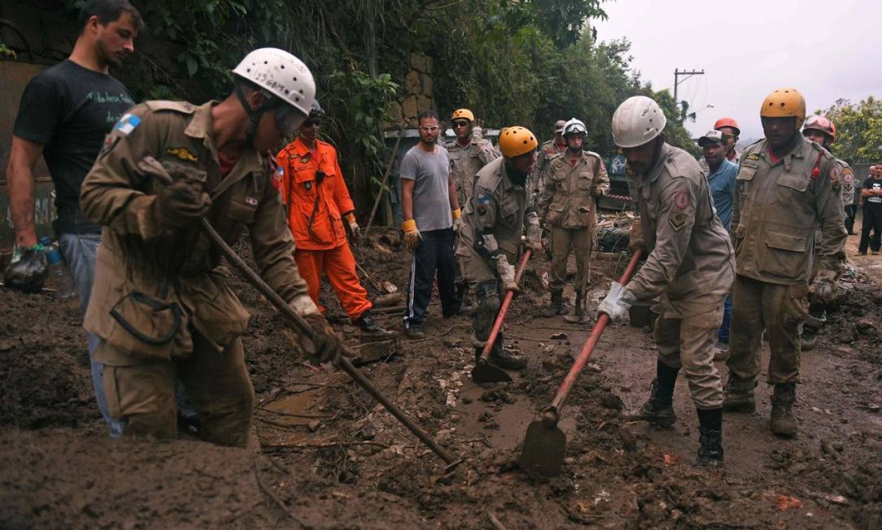 Bombeiros e voluntários são vistos durante uma missão de resgate após um deslizamento de terra gigante no bairro de Caxumbu Foto: Mauro Pimentel / AFP