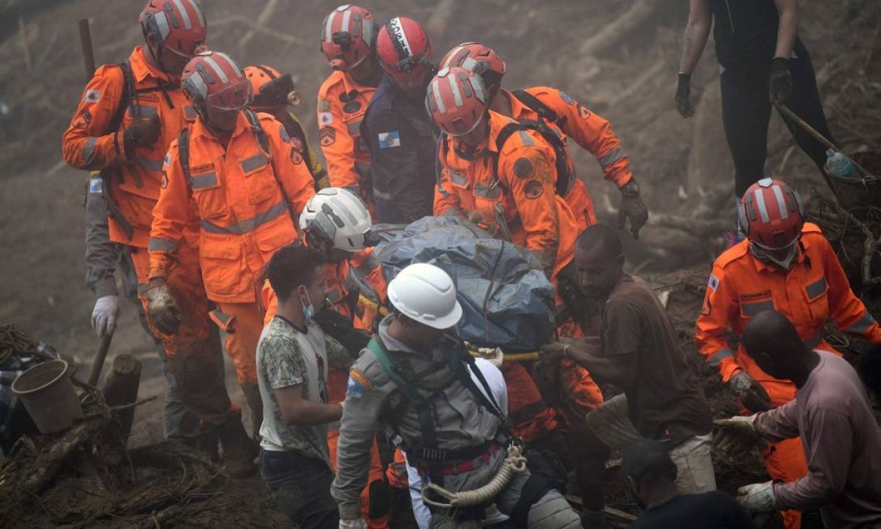 Equipes de resgate carregam o cadáver de uma vítima após um deslizamento de terra Foto: Mauro Pimentel / AFP