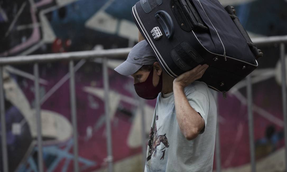 Lean Peixoto carrega pertences em uma mala deixando sua casa no Morro da Oficina Foto: Alexandre Cassiano / Agência O Globo
