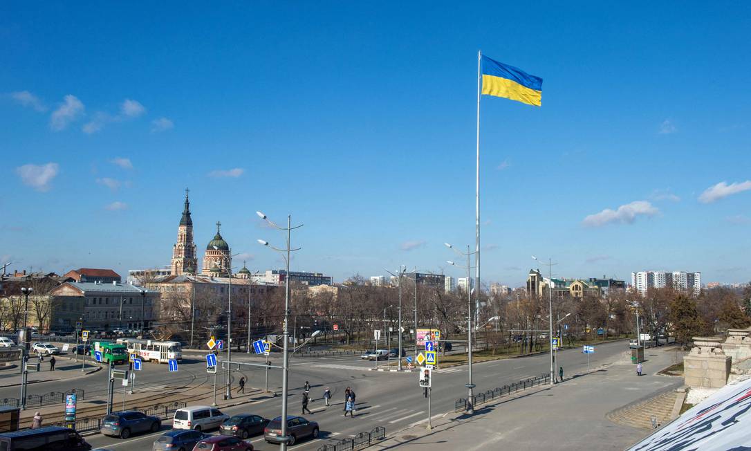 Bandeira ucraniana tremula em praça no centro de Kharkiv, cidade a cerca de 40 km da fronteira com a Rússia Foto: SERGEY BOBOK / AFP
