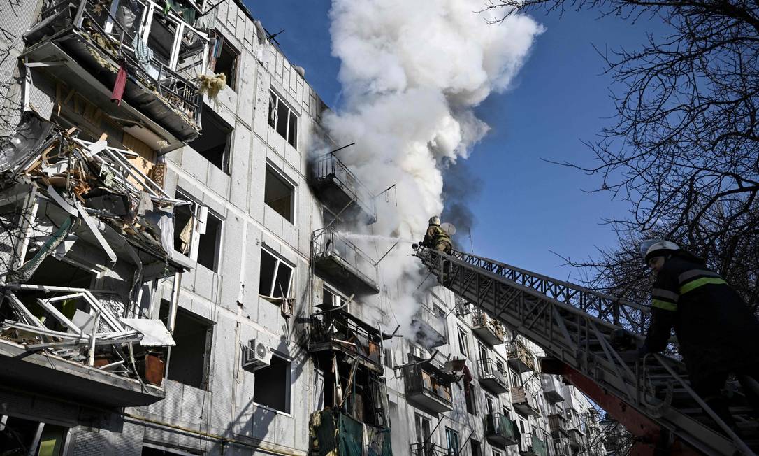 Bombeiros controlam incêndio em um prédio após bombardeios na cidade de Chuguiv, no leste da Ucrânia Foto: ARIS MESSINIS / AFP