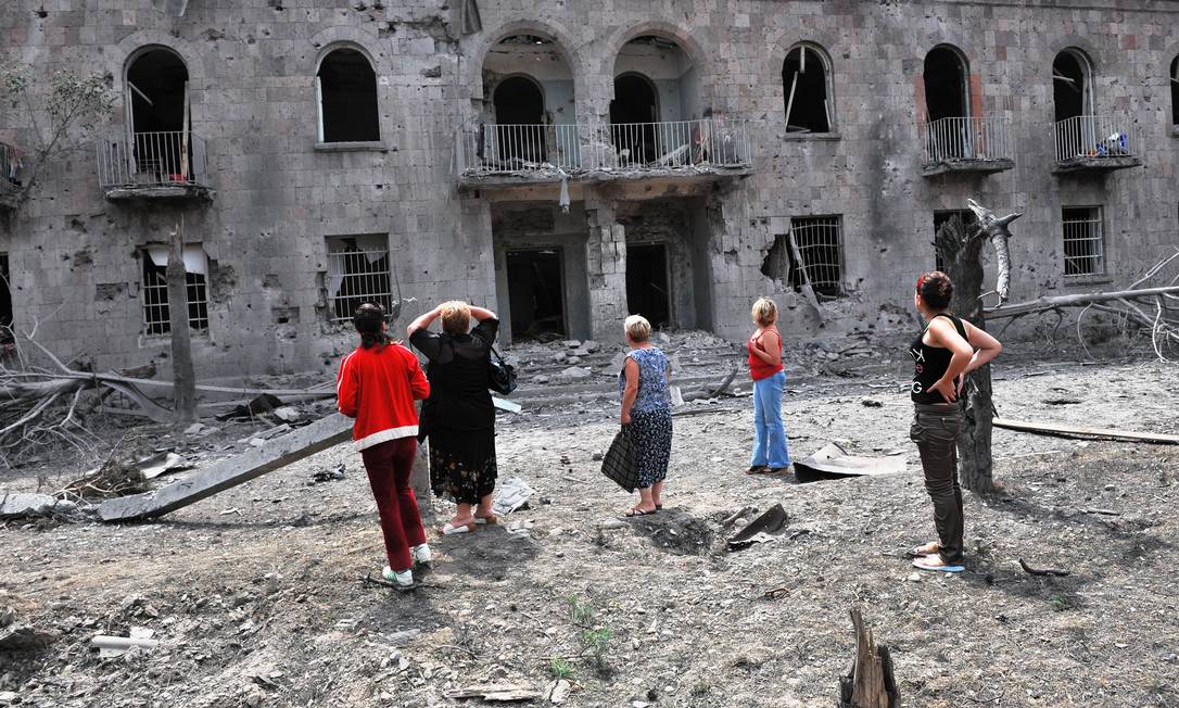 Georgianos observam prédio atingido por bombardeios russos na cidade de Gori, no dia 9 de agosto de 2008 Foto: DIMITAR DILKOFF / AFP