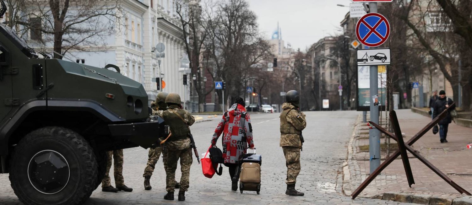 Mulher passa por militares ucranianos que guardam uma estrada, depois que a Rússia começou a invadir o país Foto: UMIT BEKTAS / REUTERS/24-02-2022