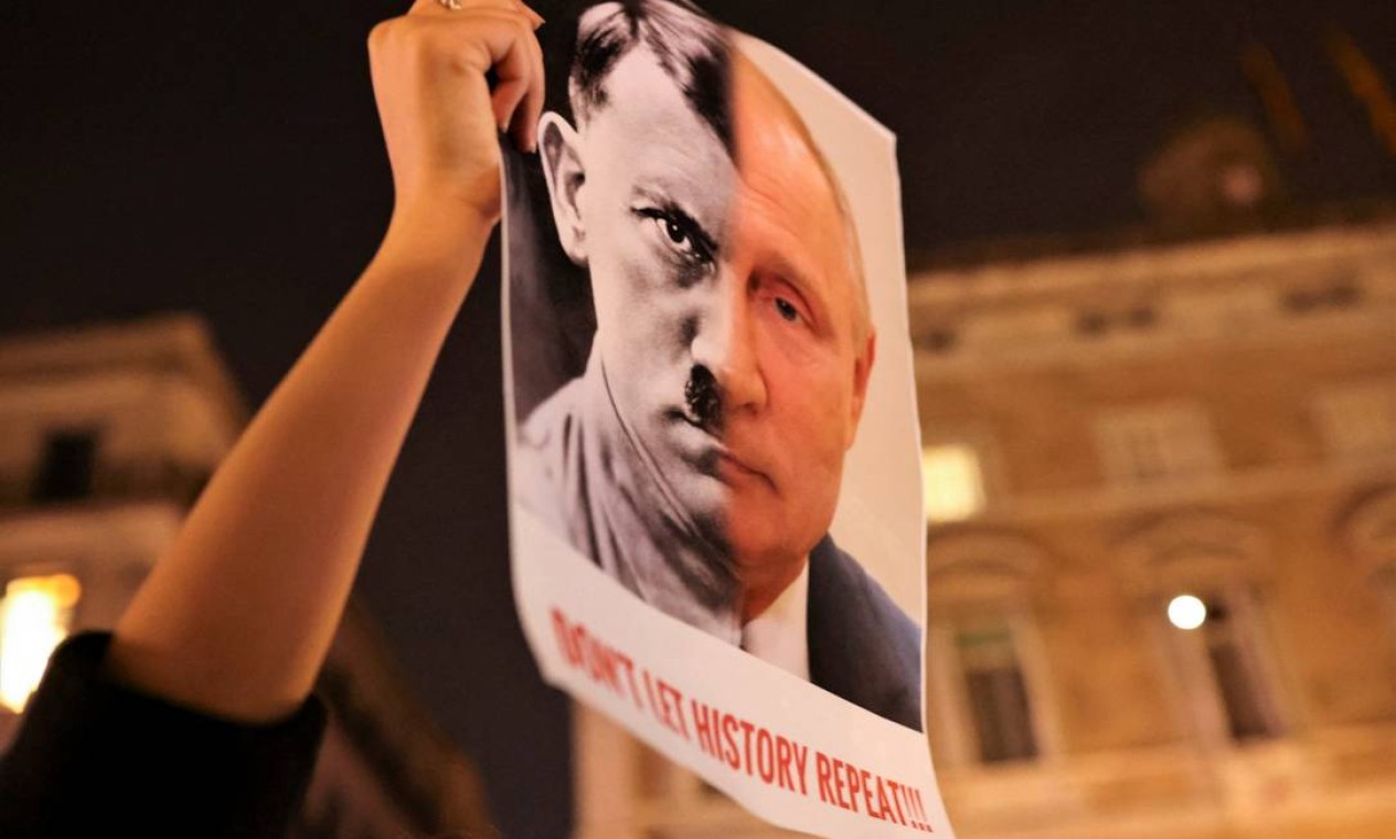Manifestante exibe cartaz com os rostos de Vladimir Putin e do ditador nazista Adolf Hitler durante um protesto em Barcelona, Espanha Foto: NACHO DOCE / REUTERS