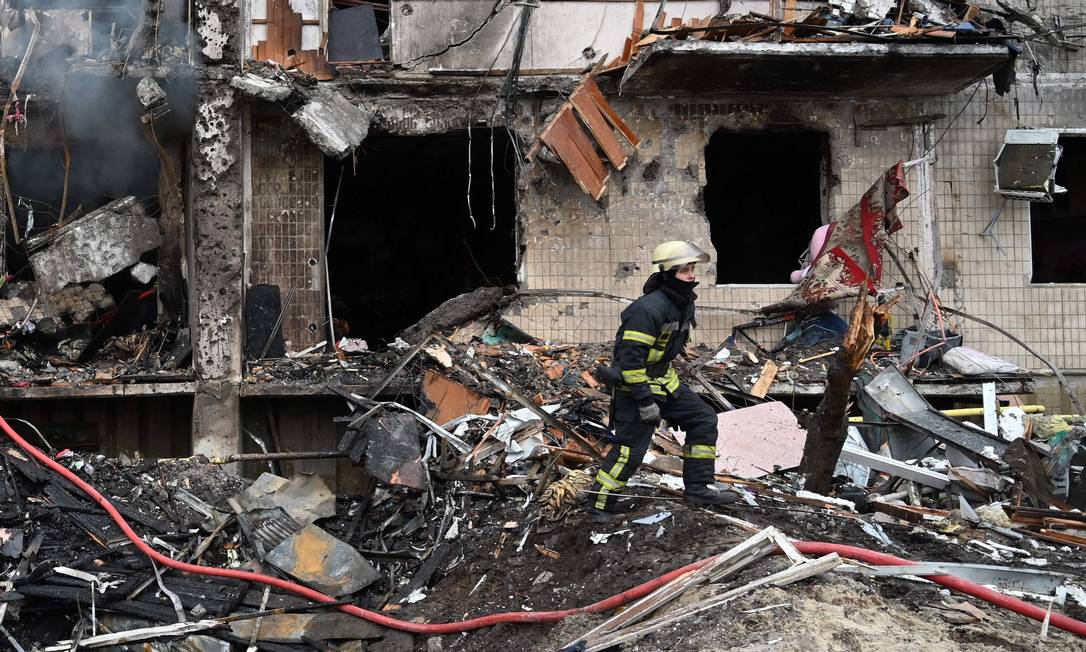 Bombeiros trabalham em um prédio residencial danificado na rua Koshytsa, um subúrbio da capital ucraniana Kiev, onde um bombardeio militar supostamente atingiu explosões ouvidas na capital Foto: GENYA SAVILOV / AFP