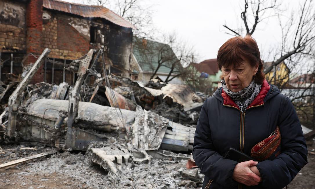 Uma pessoa caminha em torno dos destroços de uma aeronave não identificada que colidiu com uma casa em uma área residencial, depois que a Rússia lançou uma operação militar maciça contra a Ucrânia, em Kiev, Ucrânia Foto: UMIT BEKTAS / REUTERS