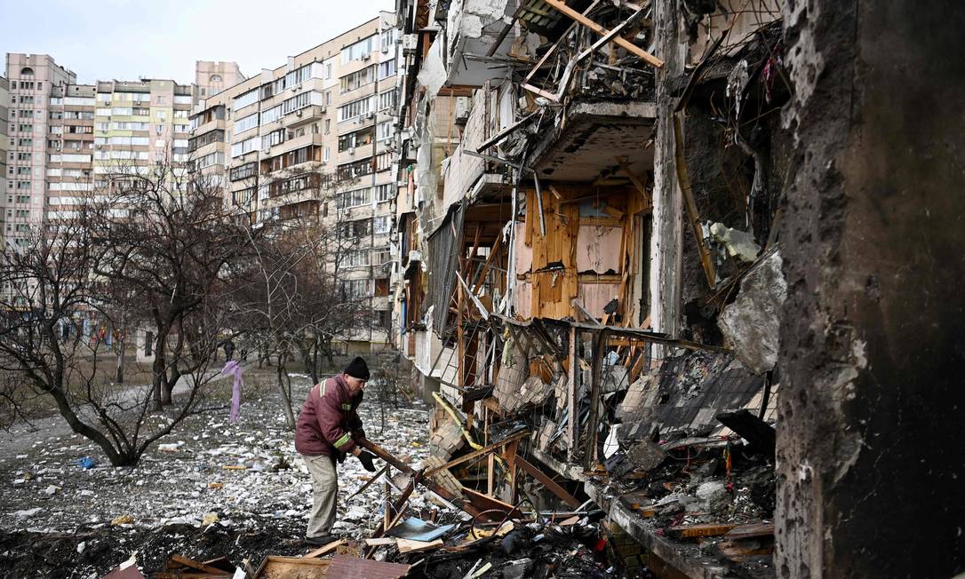 Um homem limpa destroços em um prédio residencial danificado na rua Koshytsa, um subúrbio da capital ucraniana Kiev Foto: DANIEL LEAL / AFP