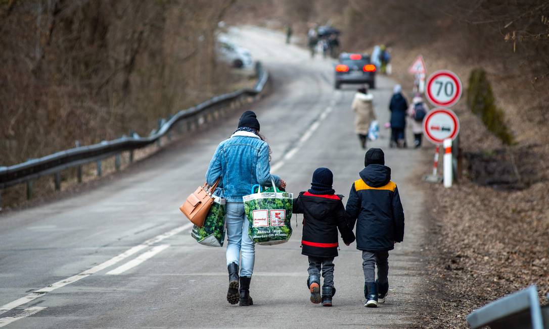 Mulher carrega bolsas com duas crianças após sair da Ucrânia e cruzar a cruzar a fronteira com a Eslováquia Foto: Peter Lazer / AFP