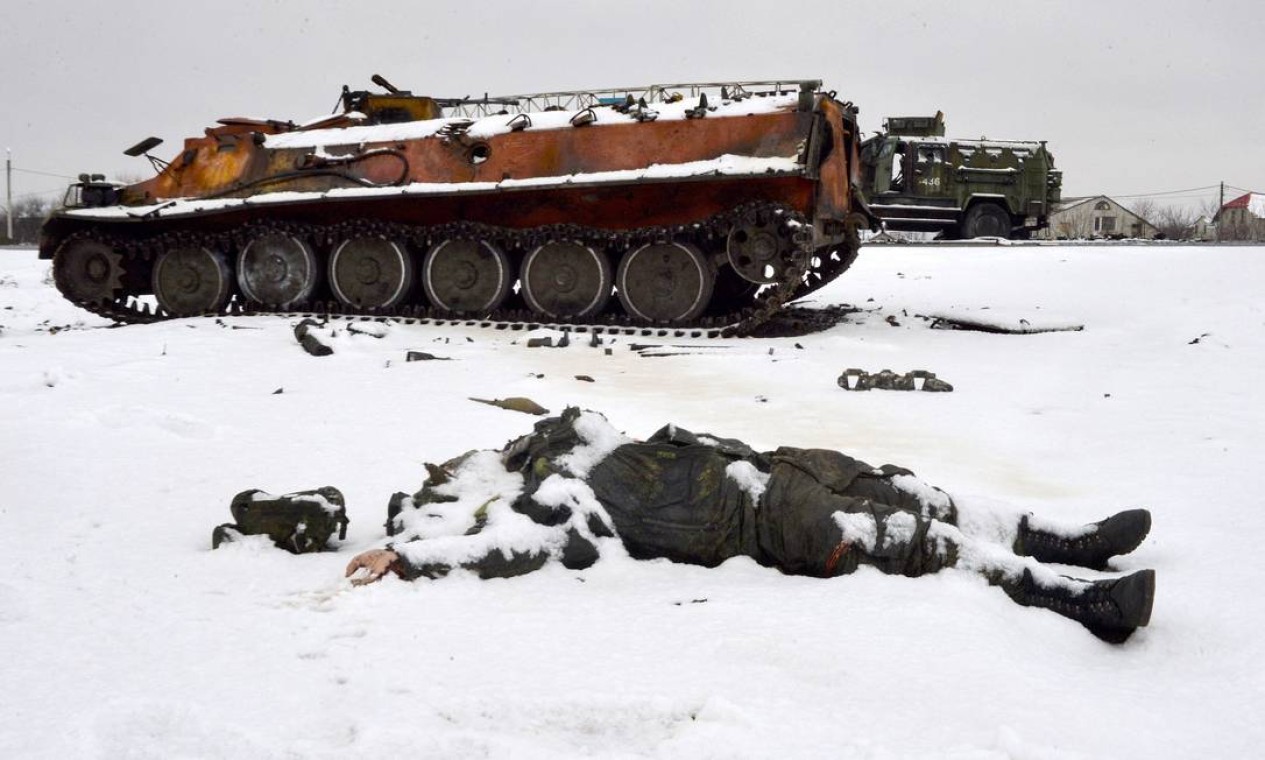 Corpo de um militar russo está perto de veículos militares russos destruídos na beira da estrada nos arredores de Kharkiv Foto: SERGEY BOBOK / AFP - 26/02/2022