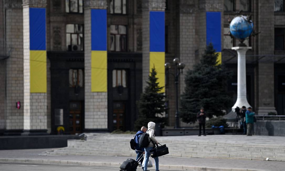 Homens carregam malas na região central de Kiev Foto: DANIEL LEAL / AFP