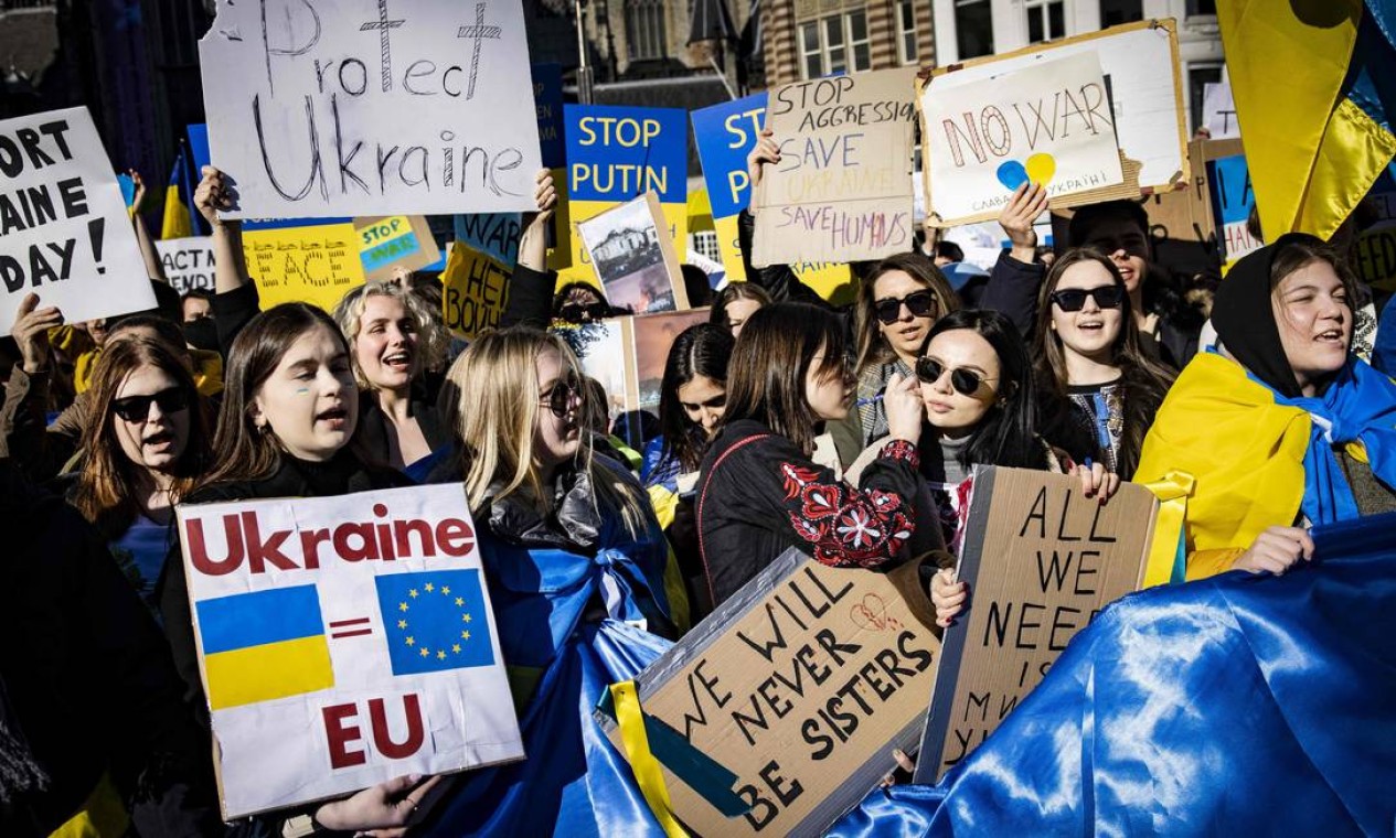 Manifestantes em Amsterdã, Holanda, seguram cartazes com as cores das bandeiras ucranianas durante uma manifestação na Praça Dam contra a invasão russa à Ucrânia Foto: RAMON VAN FLYMEN / AFP