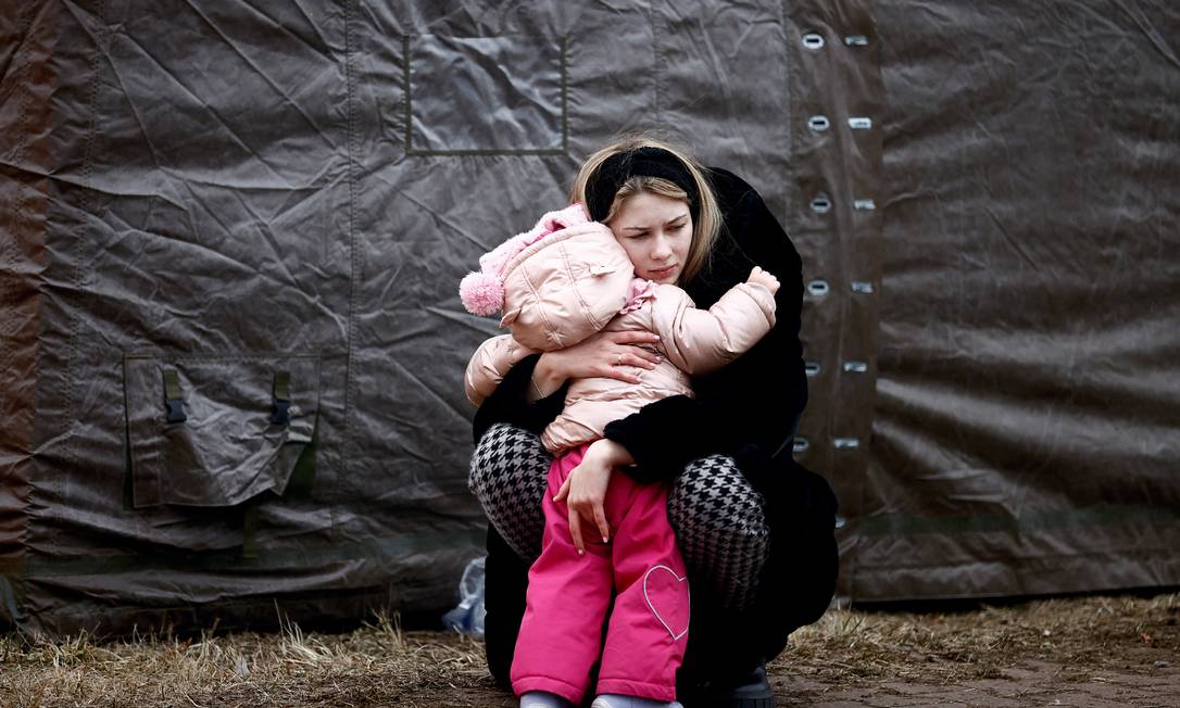 Mulher fugindo da invasão russa da Ucrânia abraça criança em acampamento temporário em Przemysl, Polônia Foto: YARA NARDI / REUTERS