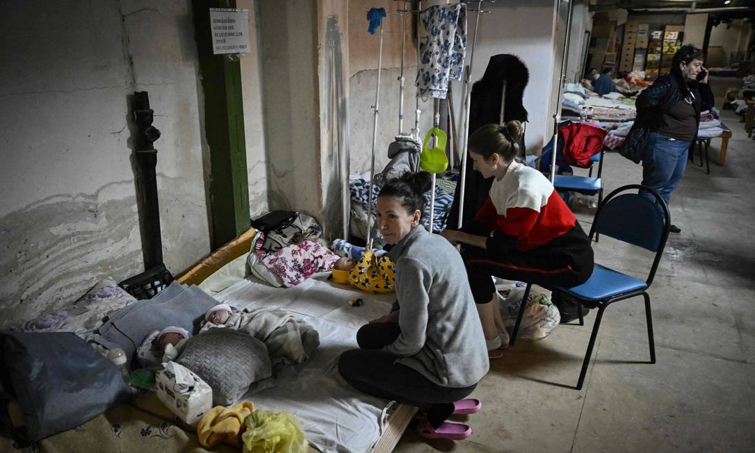 Mulheres cuidam de seus bebês no centro de pediatria depois que a unidade foi transferida para o porão do hospital que está sendo usado como abrigo antiaéreo, em Kiev Foto: ARIS MESSINIS / AFP