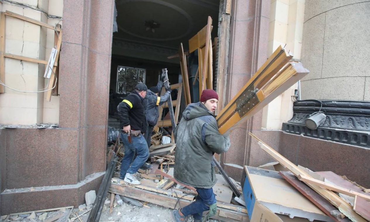 Pessoas removem detritos do lado de fora do prédio da administração regional. Cidade, em grande parte de língua russa perto da fronteira, tem uma população de cerca de 1,4 milhão Foto: VYACHESLAV MADIYEVSKYY / REUTERS