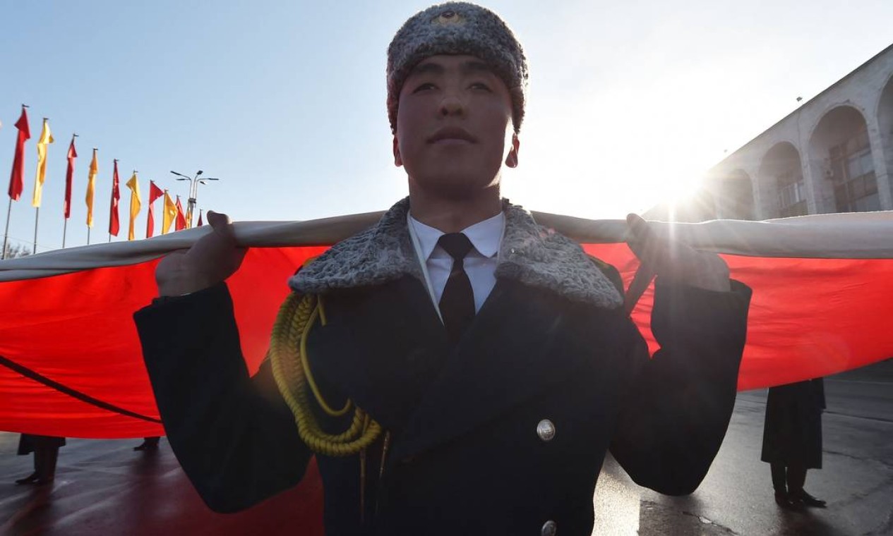 Guardas de honra do Quirguistão carregam enorme bandeira nacional durante desfile comemorando o Dia da Bandeira Nacional na praça central Ala-Too, em Bishkek Foto: VYACHESLAV OSELEDKO / AFP