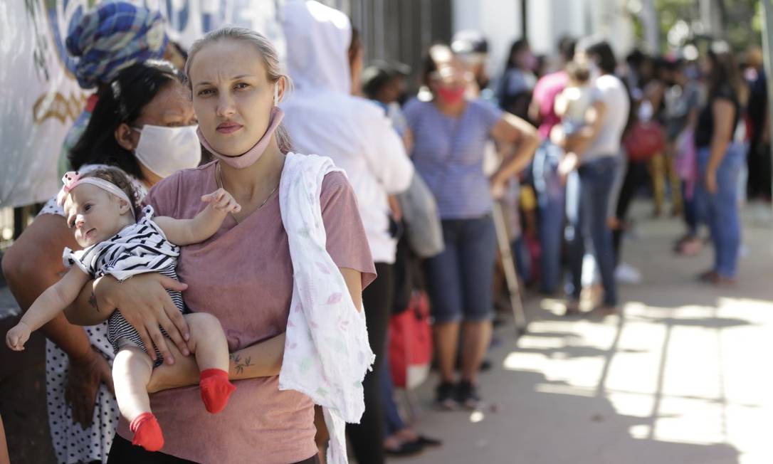 A dona de casa Yane Chaves, com a filha Anne, de dois meses, em fila para tentar conseguir uma cesta básica Foto: Roberto Moreyra / Agência O Globo