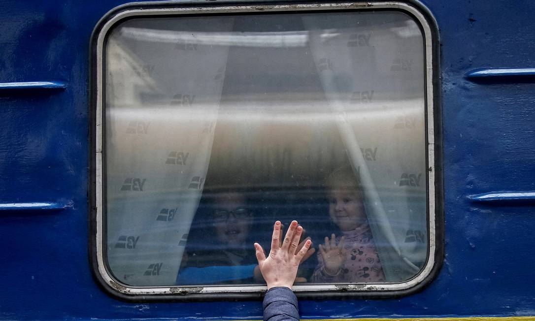 Crianças olham da janela de um trem de evacuação de Kiev para Lviv enquanto se despedem de seu pai na estação central de Kiev Foto: GLEB GARANICH / REUTERS