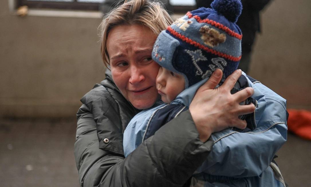 Mãe segura seu filho enquanto tenta embarcar em um trem para a Polônia em uma estação de trem em Lviv, oeste da Ucrânia Foto: DANIEL LEAL / AFP