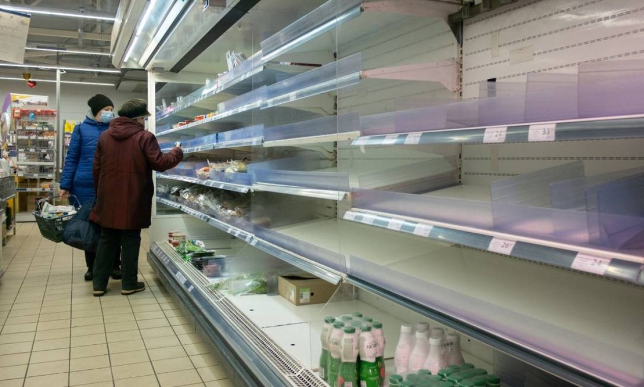 Moradores locais são vistos em frente a prateleiras parcialmente vazias em um supermercado em Kiev, Ucrânia Foto: MYKHAILO MARKIV / REUTERS