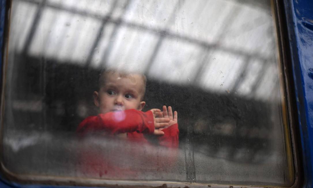 Criança olha pela janela de uma carruagem enquanto um trem se prepara para partir de uma estação em Lviv, oeste da Ucrânia, a caminho da cidade de Uzhhorod, perto da fronteira com a Eslováquia Foto: DANIEL LEAL / AFP
