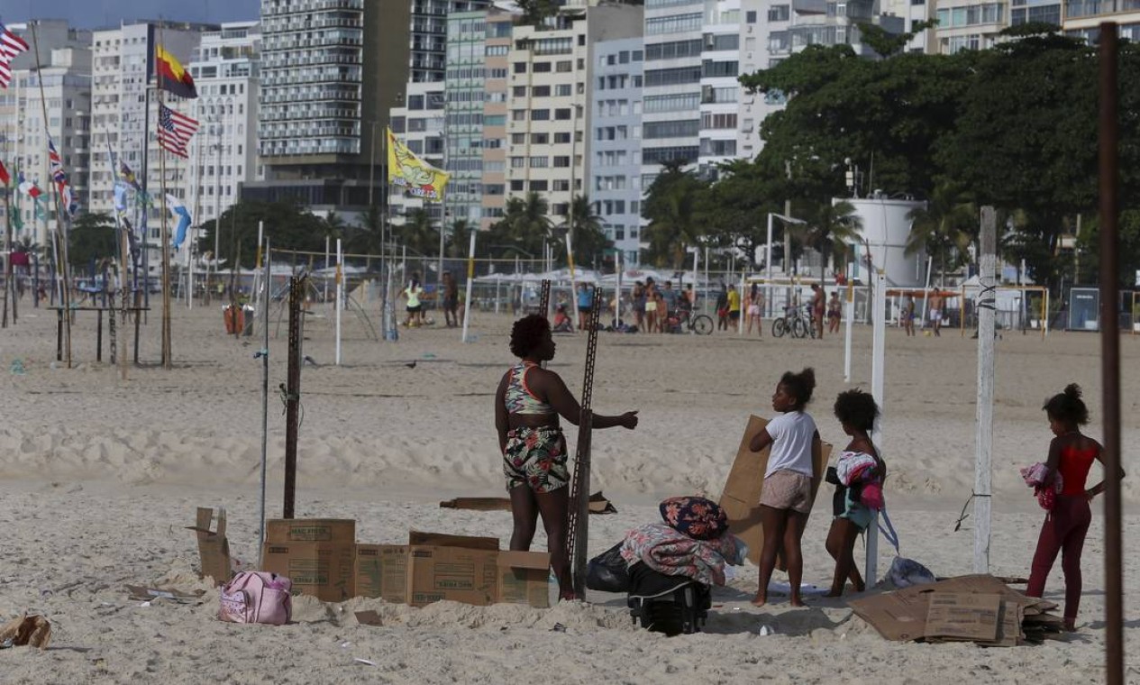 Adultos e crianças ajudam a desmontar a casa improvisada na orla de Copacabana, onde passaram a noite: de dia, estacas são usadas por barraqueiros da praia Foto: Fabiano Rocha / Agência O Globo