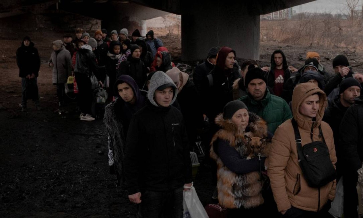 Ucranianos aguardam para cruzar o rio Irpin sobre os escombros da ponte destruída dias antes por suas próprias tropas para impedir a chegada dos russos a Kiev Foto: JEDRZEJ NOWICKI/AGENCJA WYBORCZA / Agencja Wyborcza.pl via REUTERS