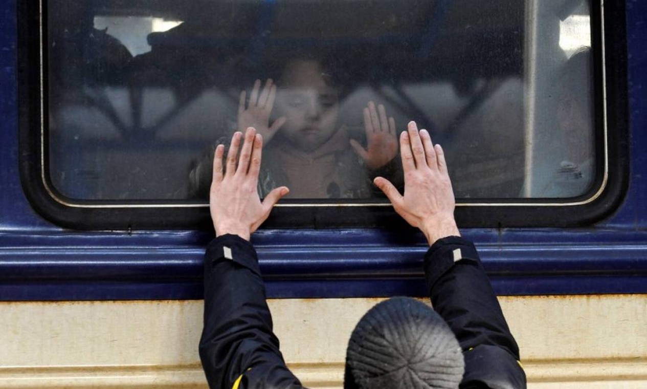 Pai se despede do filho em um trem de evacuação na estação central de Kiev Foto: SERGEI CHUZAVKOV / AFP