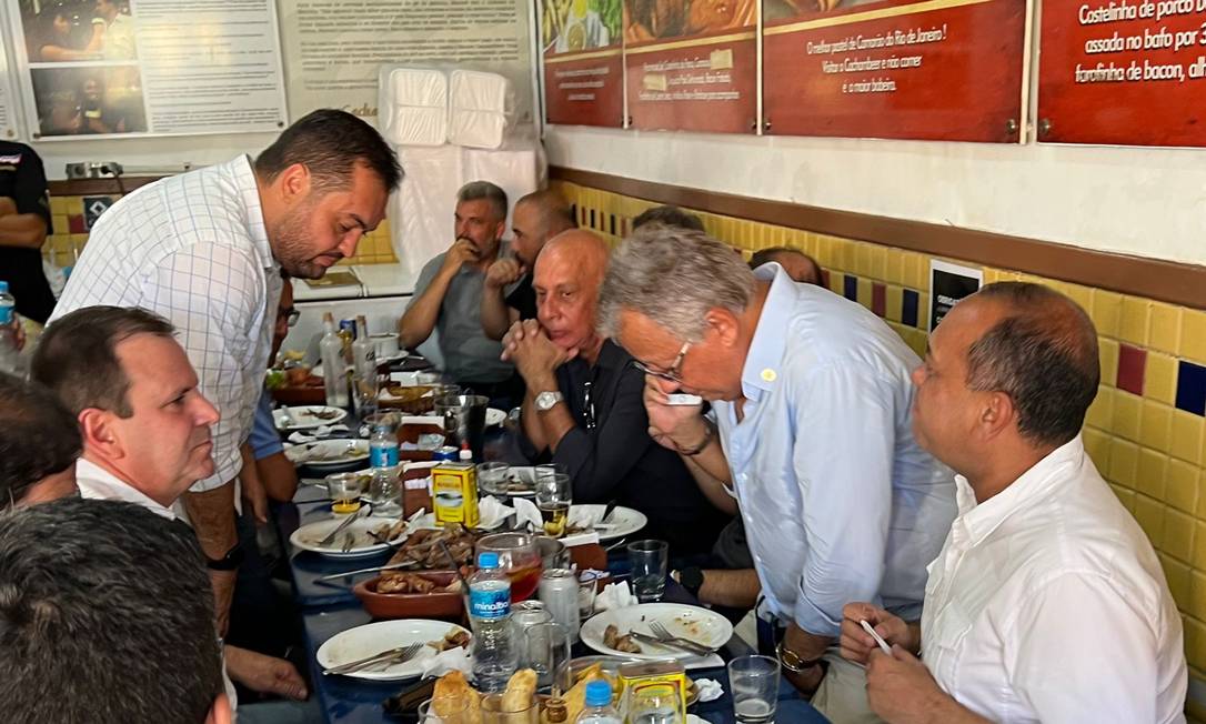 Paes (à esquerda, em primeiro plano) e Castro, sentando-se a seu lado, em almoço na Zona Norte do Rio: correligionários do governador estiveram presentes Foto: Reprodução